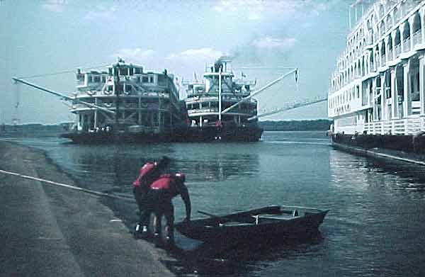 Two men about to shove off in a dinghy, on the first day in history that all three Queen riverboats were docked in Paducah at the same time